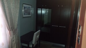 A room with a bed, a chair, a small table, and a wardrobe. - Hard Break Hotel and Suite (Enugu)