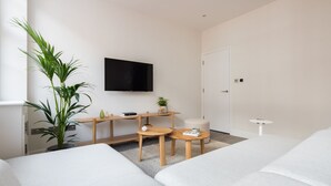 Une chambre d’hôtel moderne équipée d’un lit, d’un bureau, d’une chaise, d’une télévision et d’une plante en pot.