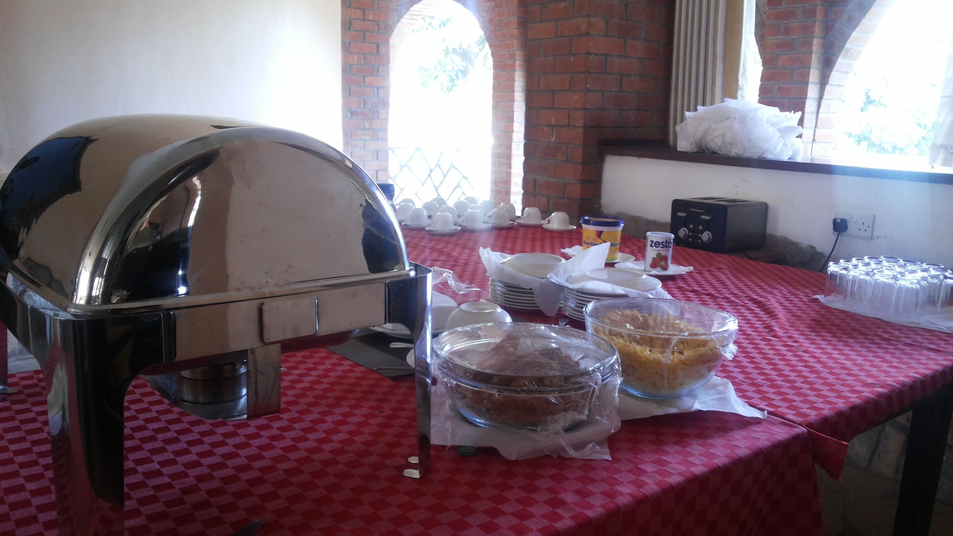 A buffet setup with a grill, bowls of food, and a toaster.