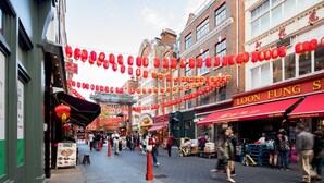 Une rue animée, bordée de lanternes rouges, de boutiques et où l’on peut voir des gens qui se promènent.
