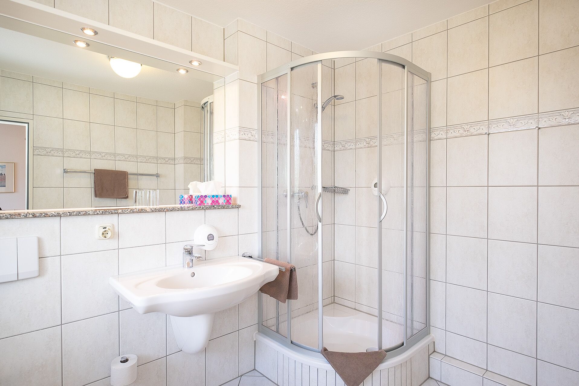 Une salle de bain avec une douche à parois de verre, un lavabo et un miroir.