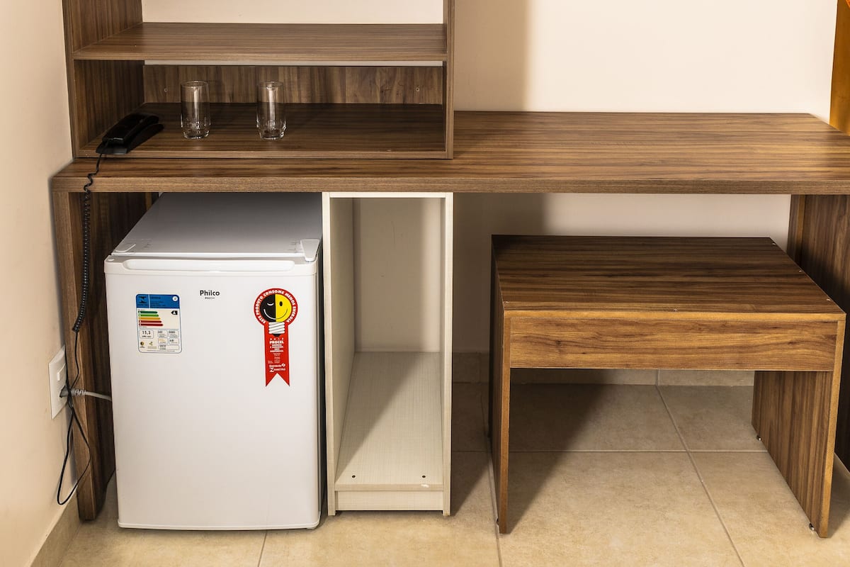 Una kitchenette compacta con refrigerador integrado, un lavamanos pequeño y un banco de madera.