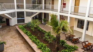 Un atrio de varios niveles con un jardín central, asientos al aire libre y una escalera.