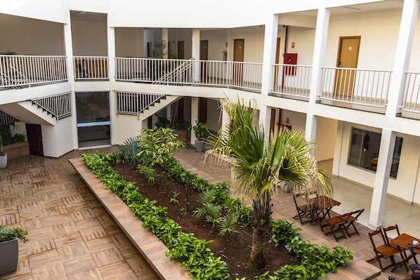 A multi-level atrium with a central garden, outdoor seating, and a staircase.