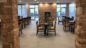 A restaurant with stone walls, multiple tables and chairs, and a fireplace.