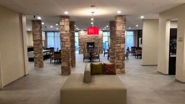 A spacious lobby with a central seating area, stone pillars, and a modern fireplace.