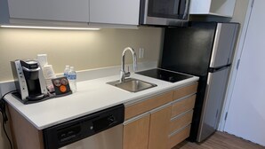 A modern kitchen with a dishwasher, sink, and a microwave above the stove.