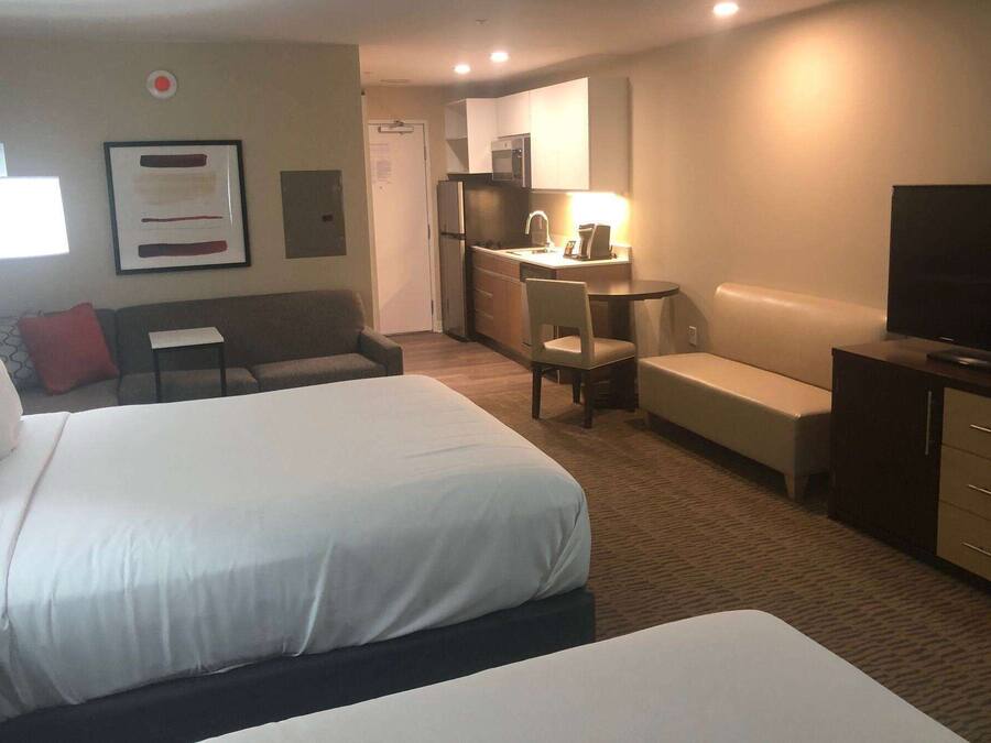 Een hotelkamer met twee bedden, een bureau, een televisie en een kitchenette.