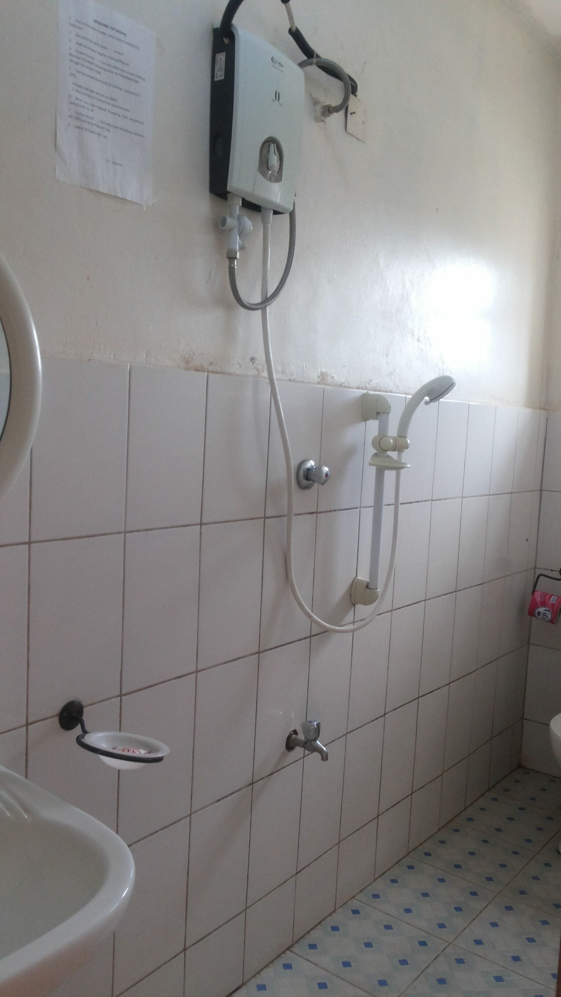 Une salle de bain équipée d’un lavabo, de toilettes et d’une douche murale.
