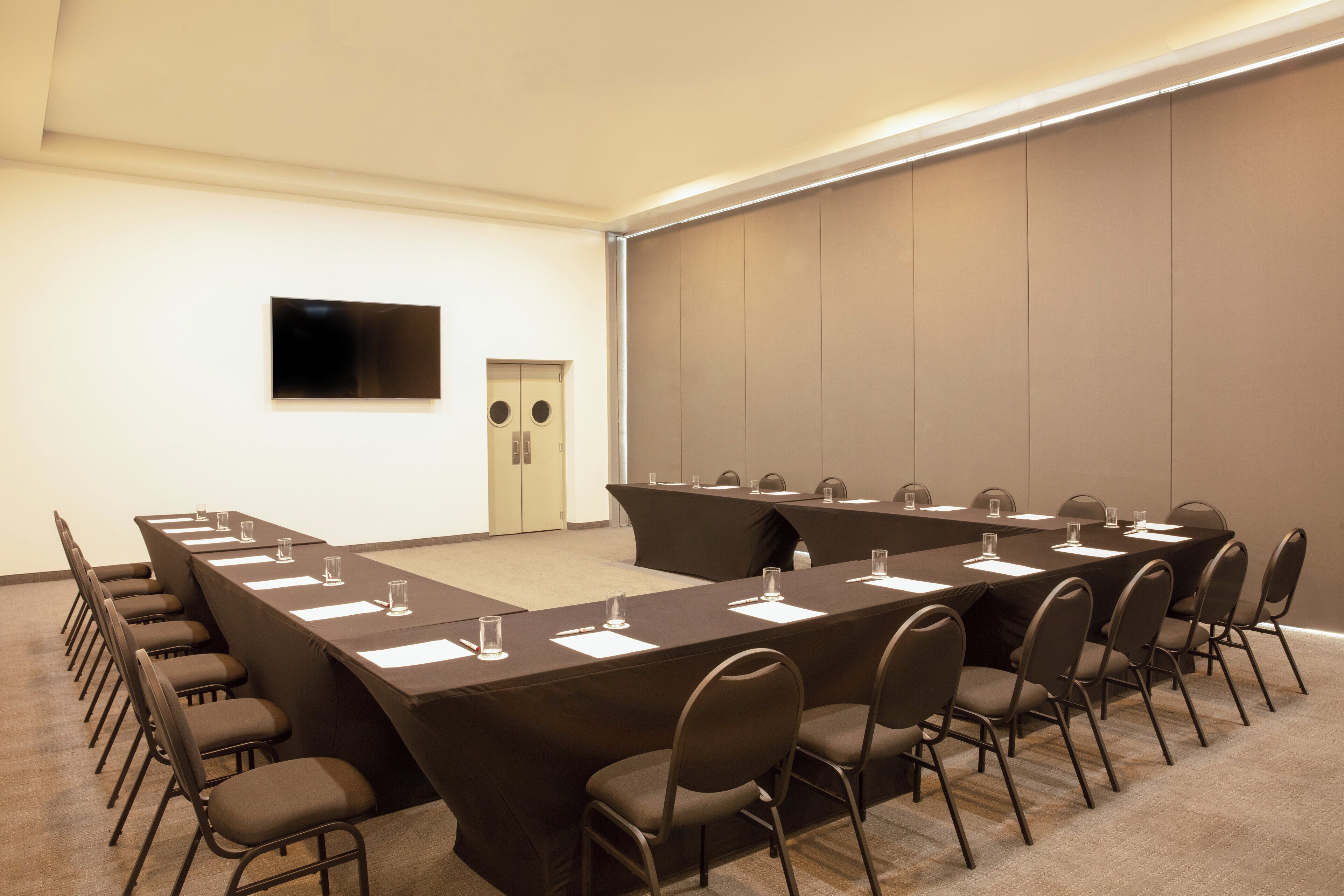 A conference room with a long table, chairs, and a flat-screen TV on the wall.