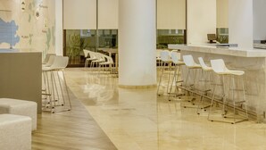 Una cocina moderna con barra, taburetes blancos y luminarias colgantes.