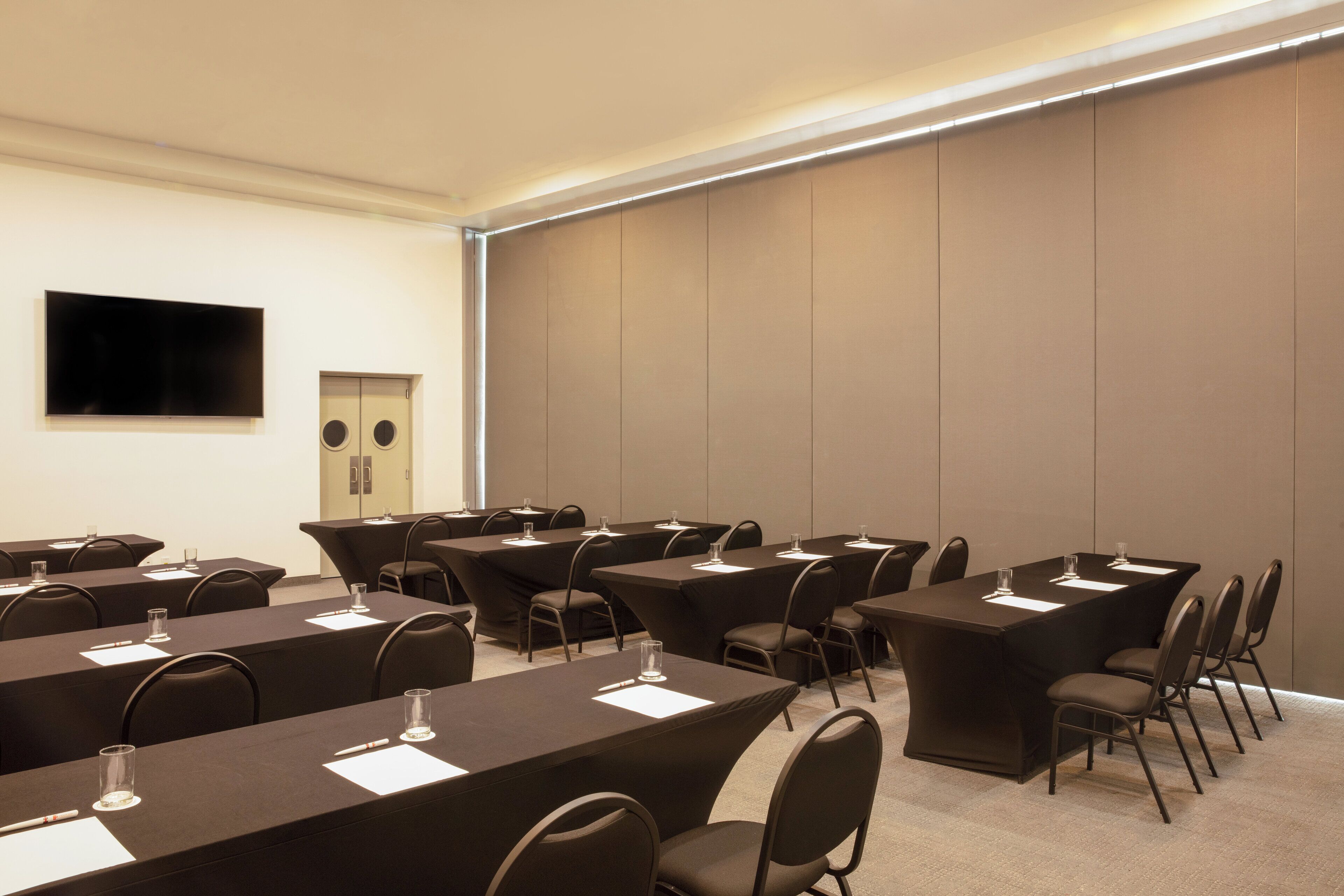 A conference room with multiple tables and chairs, equipped with nameplates and water glasses.