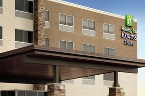 Een Holiday Inn Express & Suites gebouw met een modern ontwerp, met een plat dak, grote ramen en een gevel van natuursteen.