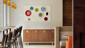 Un interior moderno con una zona de comedor, un mueble de madera con iconos, y un sofá estampado.