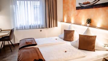 Quarto de hotel com uma cama, uma escrivaninha e uma cadeira.