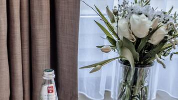 A table with a clear glass vase containing white flowers, a bottle of water, and several empty wine glasses.