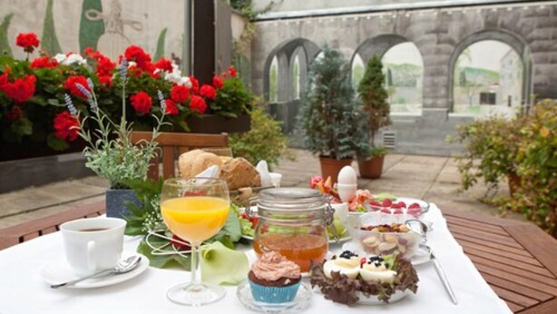 Een terras met eethoek, gedekt voor het ontbijt, met koffie, sap, gebak en een salade.