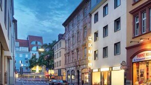 Een hotel in klassieke Europese stijl, met meerdere verdiepingen, grote ramen en een goed verlichte gevel.