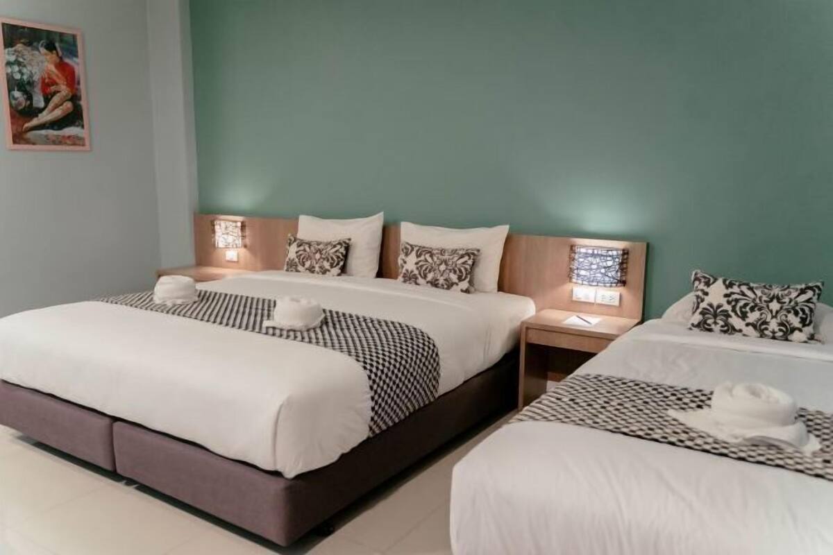 A hotel room with two beds, a nightstand, and a wall-mounted lamp.