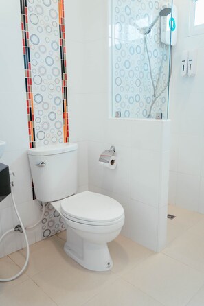 Un baño moderno con inodoro, ducha y dispensador de papel higiénico.