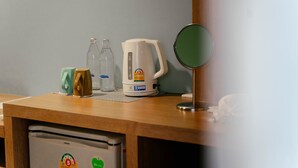 A kitchenette with a refrigerator, a kettle, a bottle, and a glass. - It's me Keawanong Hotel (Nakhon Ratchasima)