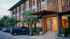 A multi-story hotel with a modern design, featuring balconies, a covered entrance, and a parking area with several cars. - It's me Keawanong Hotel (Nakhon Ratchasima)