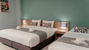 A hotel room with two beds, each with a white comforter and patterned pillows. There is a nightstand with a lamp between the beds. - It's me Keawanong Hotel (Nakhon Ratchasima)