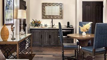 A dining area with a round table, two blue upholstered chairs, a decorative vase, and a wall-mounted artwork.