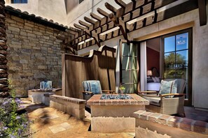 An outdoor patio area with stone walls, a fire pit, and wicker furniture.