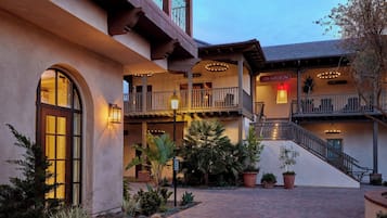 A multi-level building with a covered patio area, outdoor lighting, and potted plants.