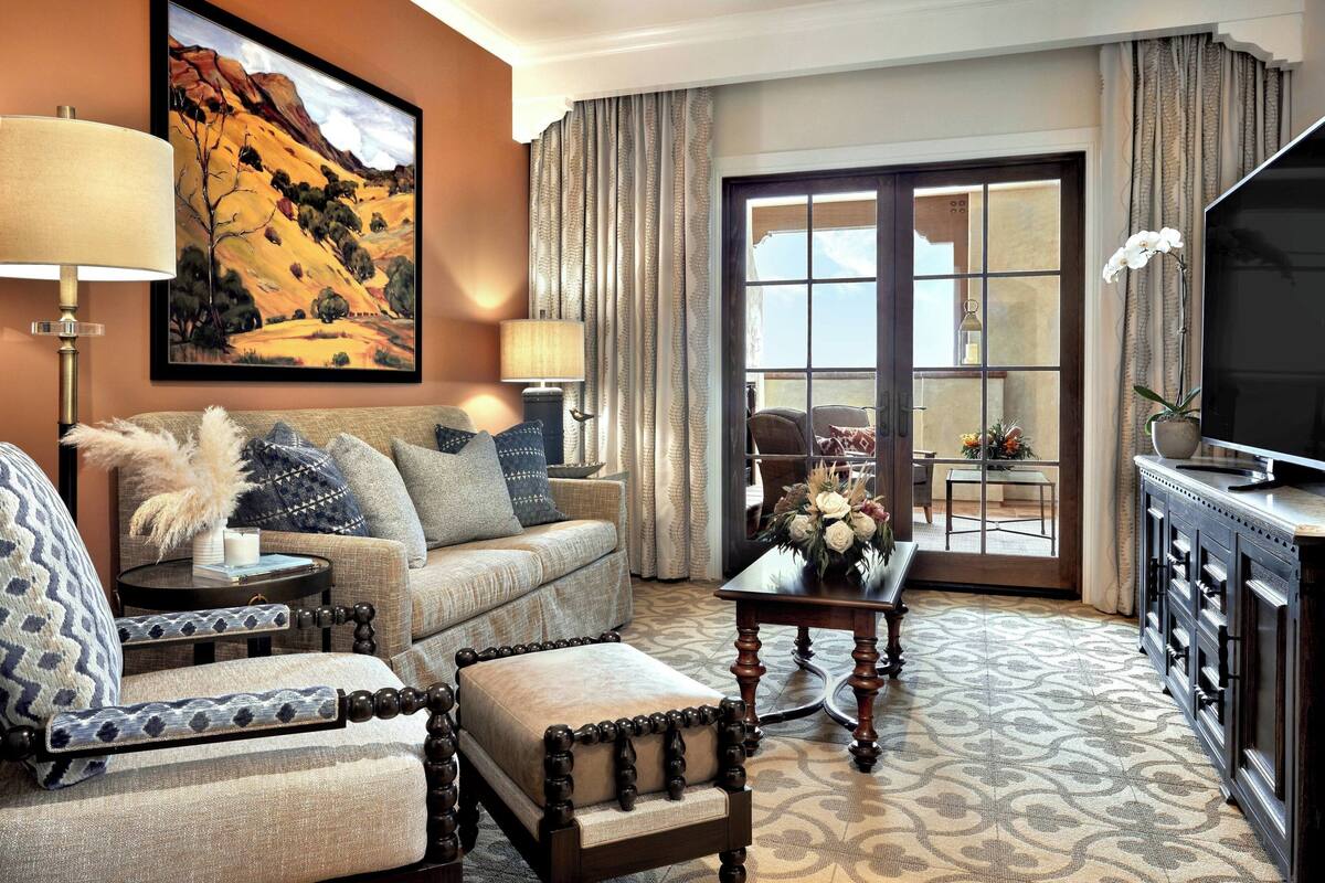 A living room with a sofa, armchair, and ottoman, a television, and a dining area with a table and chairs.