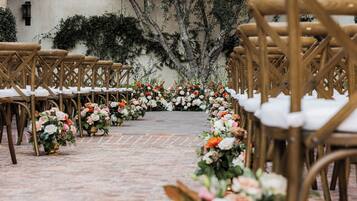 A pathway lined with chairs and floral arrangements, leading to a central area.