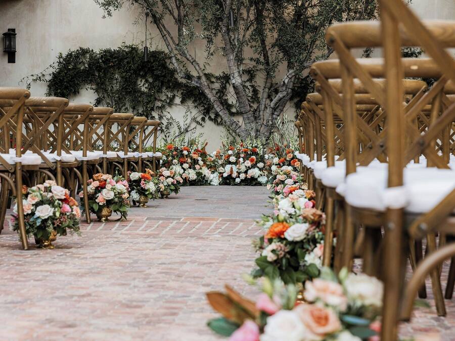 A pathway lined with chairs and floral arrangements, leading to a central area.