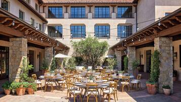 A courtyard with outdoor seating, stone pillars, and a building with multiple windows.