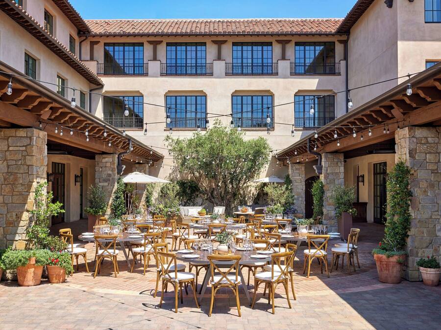 A courtyard with outdoor seating, stone pillars, and a building with multiple windows.