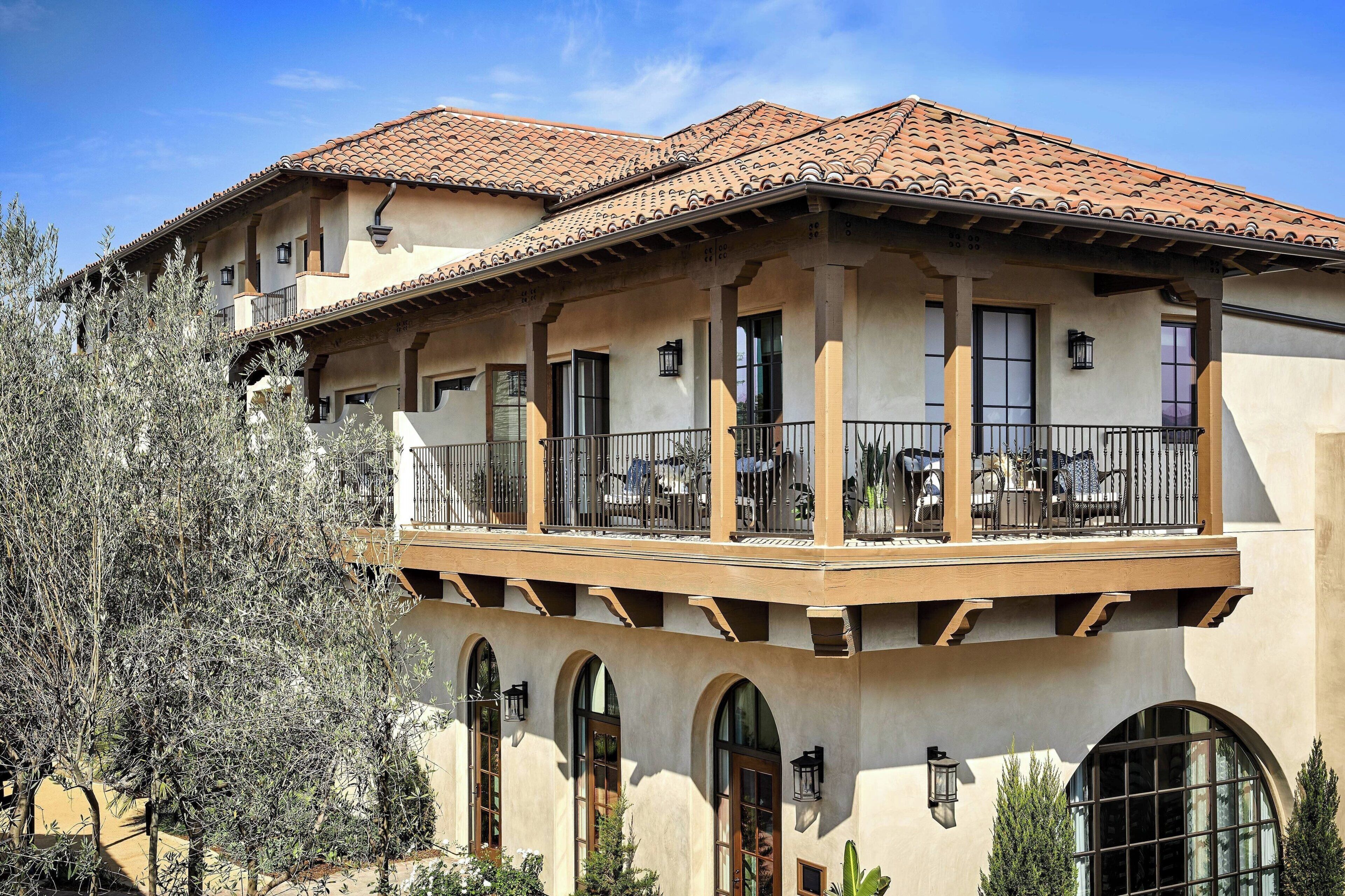 A two-story building with a balcony, arched windows, and a tiled roof.