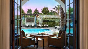An outdoor pool area with wicker furniture, a stone wall, and a pergola. - Inn at the Mission San Juan Capistrano, Autograph Collection by Marriott (San Juan Capistrano)