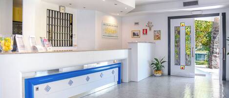 A reception area with a counter, a clock, framed pictures, and a door leading outside.