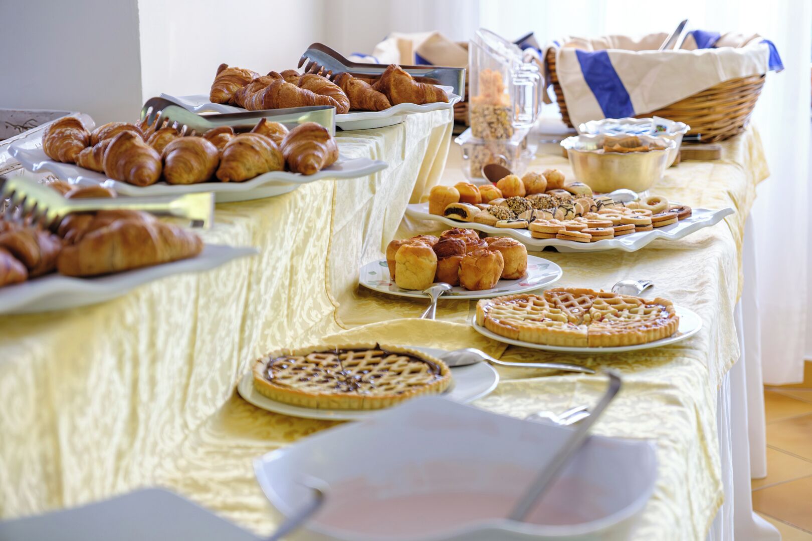 Una mesa de buffet con diversas opciones de panadería, incluyendo cruasanes, muffins y tartas.
