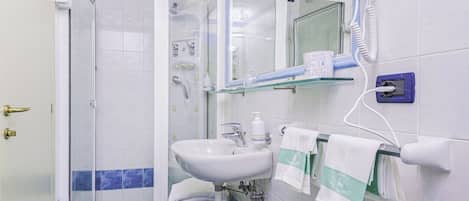 A bathroom with a shower, sink, and hairdryer.