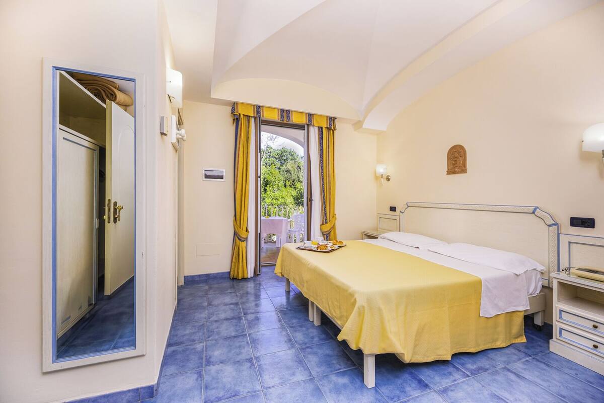 Ein Schlafzimmer mit Bett, Nachttisch und Blick ins Freie.