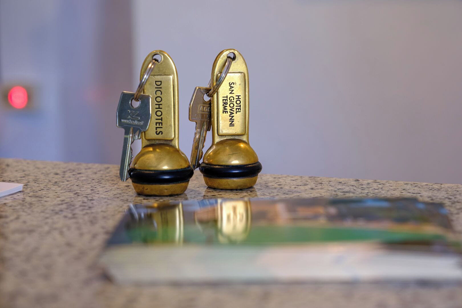 Two brass keychains with hotel names on a countertop.