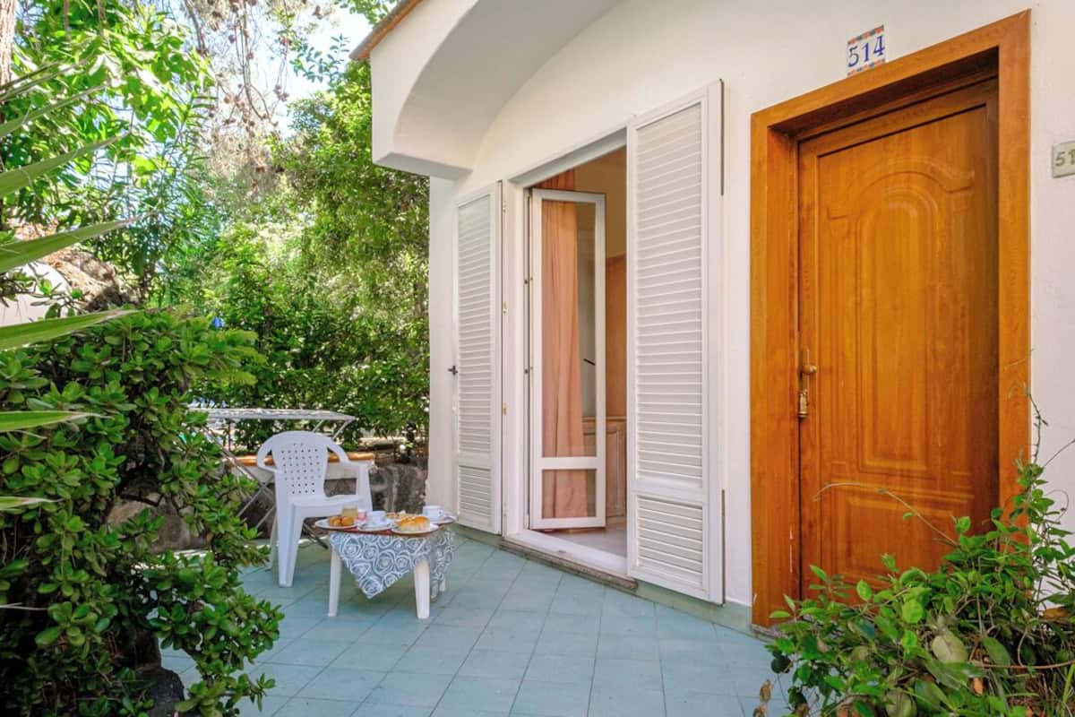 Ein Haus mit gefliestem Patio, einer Holztür und einem Fenster mit weißem Rahmen.