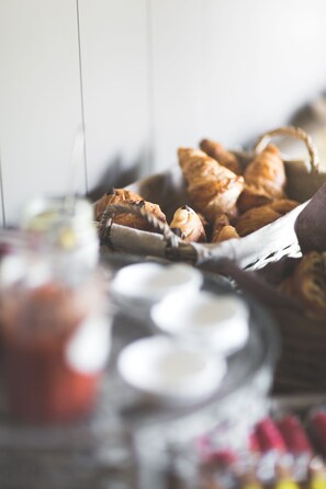 A basket of pastries and a jar of jam on a table.
