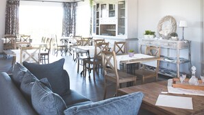 A spacious living area with a large clock, a sofa, and a dining table. - B&B Nieuwhof (Gistel)