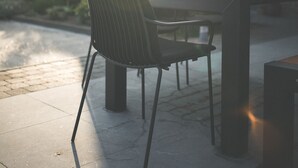 An outdoor dining area with a table and chairs, a brick building in the background, and a clear sky. - B&B Nieuwhof (Gistel)