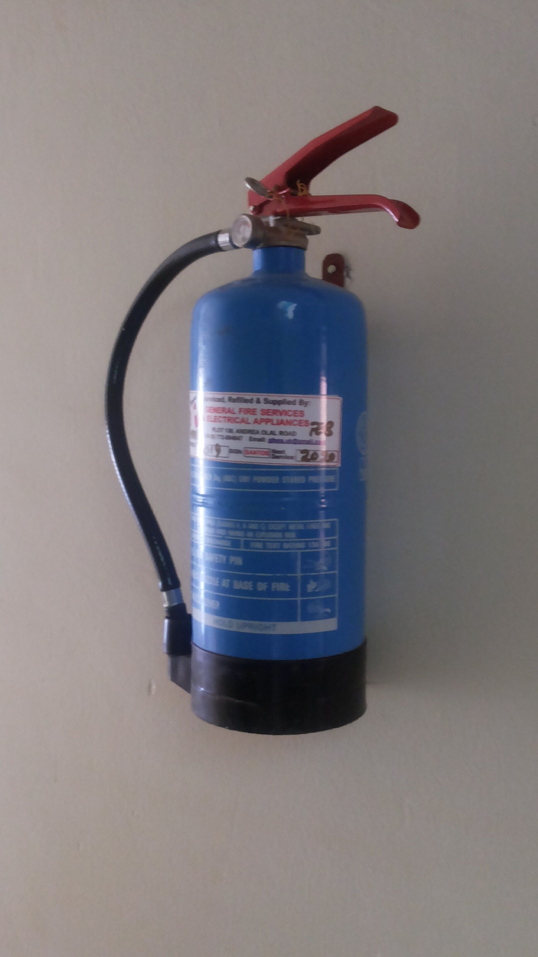 Un extincteur bleu fixé au mur.