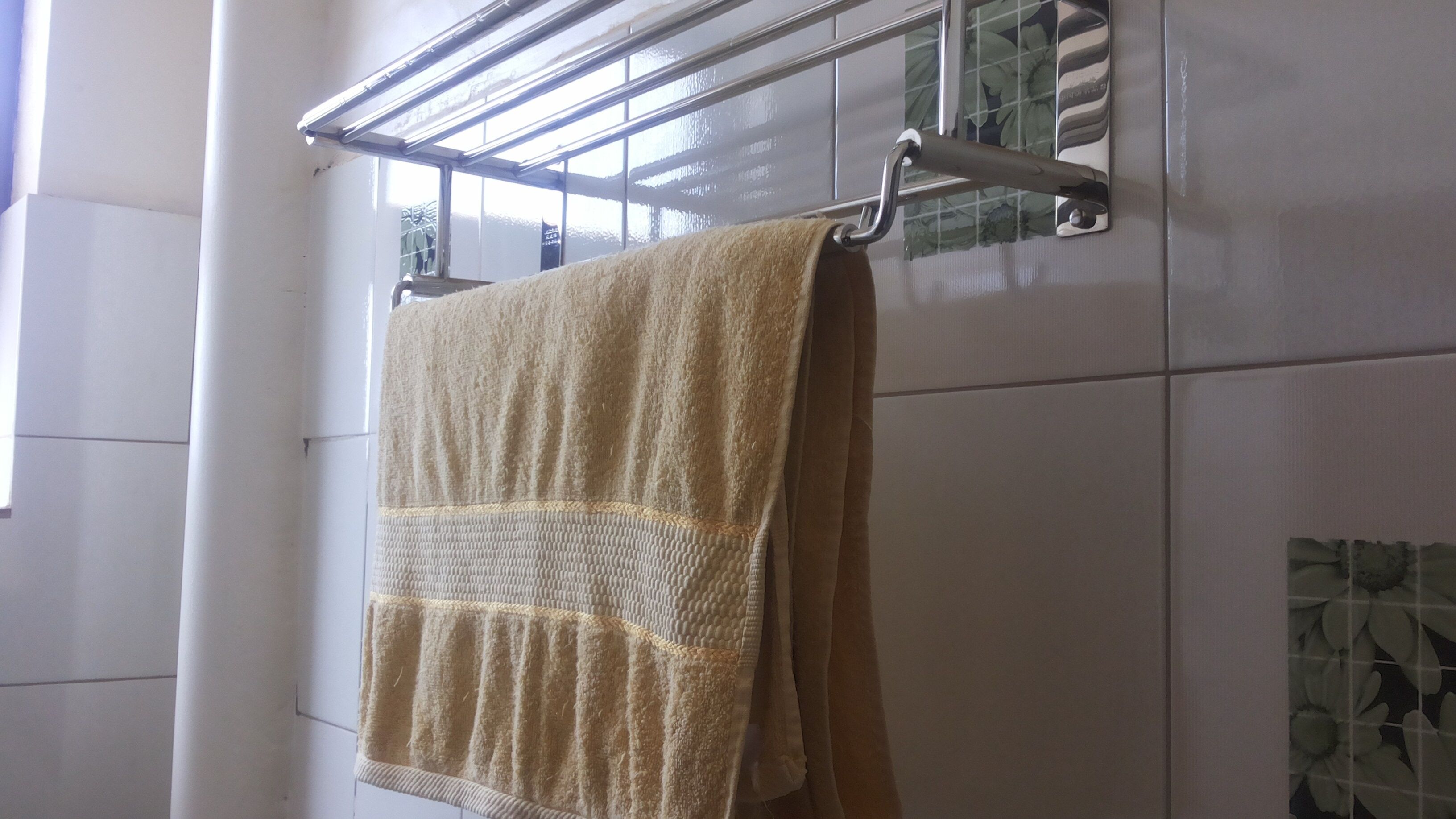 A bathroom with a towel hanging on a rack, a glass shower door, and tiled walls.