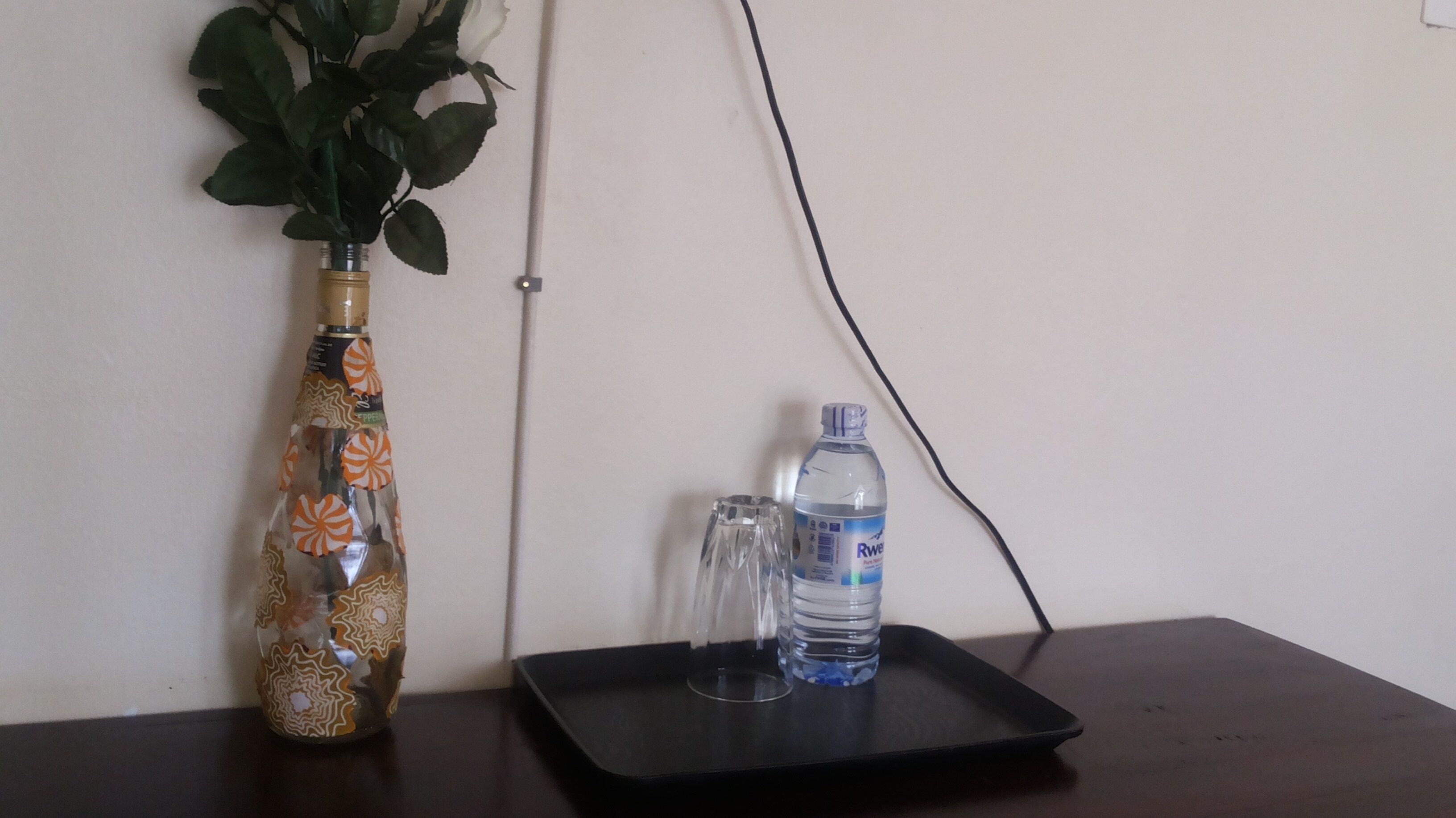 A table with a vase, a bottle of water, and a glass.