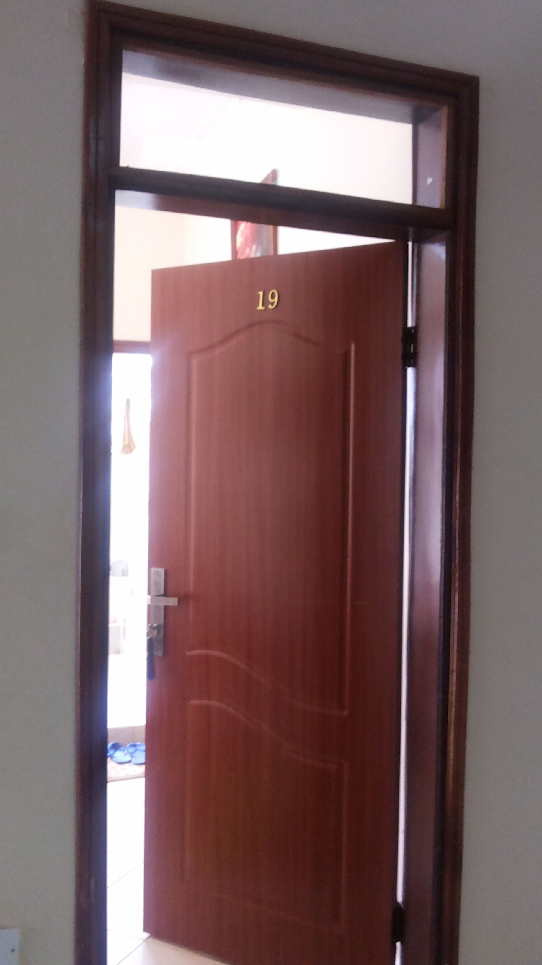 Une porte en bois fermée, portant le numéro 19, avec une poignée visible et un trou de serrure.